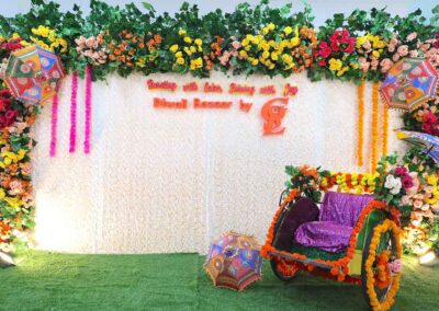 Vibrant floral photo booth by Gandhi Seva Loka, decorated with colorful flowers, umbrellas, and a traditional rickshaw for guests to take pictures.