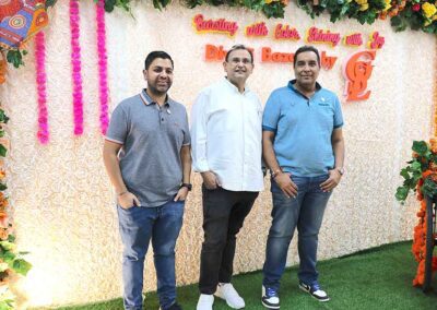 Three men posing together in front of the floral photo booth at the Diwali Bazaar in Jakarta organized by Gandhi Seva Loka.