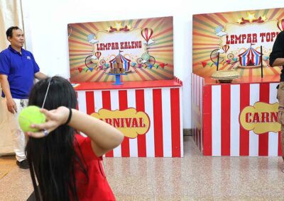 Child aiming ball at Lempar Kaleng and Lempar Topi games at Diwali Bazaar Jakarta.