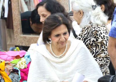 An elegant woman in a white outfit and pearl necklace smiling while attending the Diwali Bazaar organized by Gandhi Seva Loka in Jakarta,