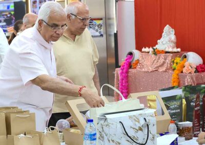Men selecting packaged snacks and festive foods at the Diwali Bazaar in Jakarta by Gandhi Seva Loka, with a Ganesh statue in the background.