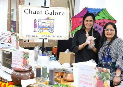 Two women smiling at the Chaat Galore stall serving Indian street food at the Diwali Bazaar in Jakarta by Gandhi Seva Loka.