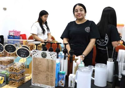 Young women selling coffee, cookies, and beverages at a modern cafe-style stall during the Diwali Bazaar in Jakarta organized by Gandhi Seva Loka.