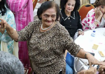 Elderly woman dancing joyfully during Raksha Bandhan celebration by Gandhi Seva Loka.