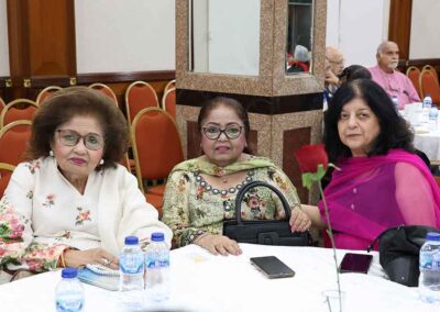 Three elegantly Indian women seated at a table during Raksha Bandhan celebration by Gandhi Seva Loka in Jakarta.